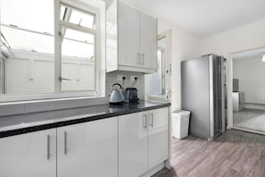 Enjoy cooking in this well-equipped kitchen with a stainless steel refrigerator, kettle, and ample counter space.