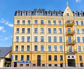 A multi-story building with a yellow facade, multiple windows, and a corner entrance.