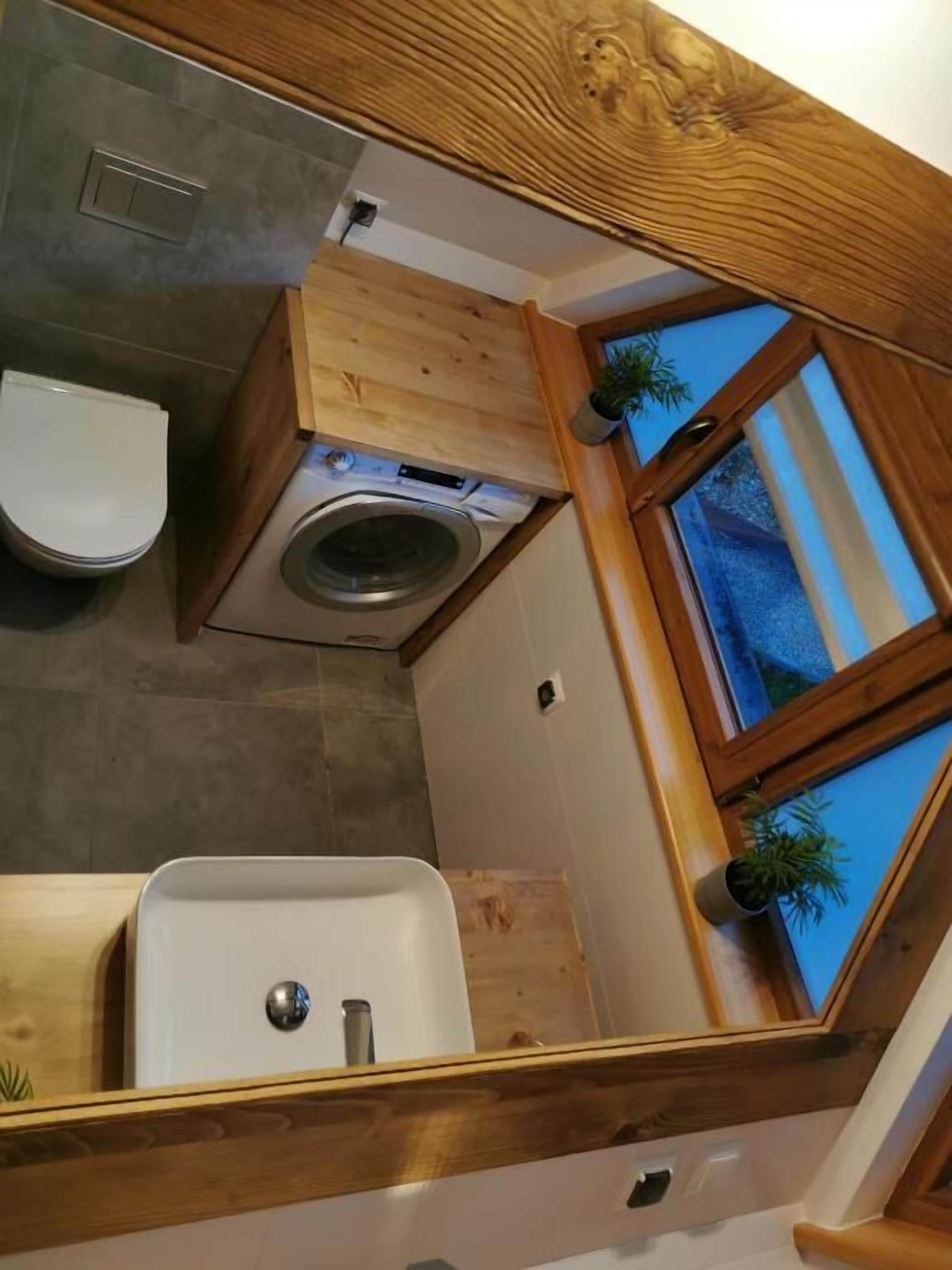 Uma cozinha compacta com máquina de lavar embutida, pia e janela com vista para o exterior.