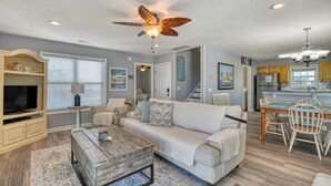 A spacious living room with a large sofa, a coffee table, and a ceiling fan. - Oceanfront 4 Bedroom, 3 Bath with Community Pool (Garden City Beach)