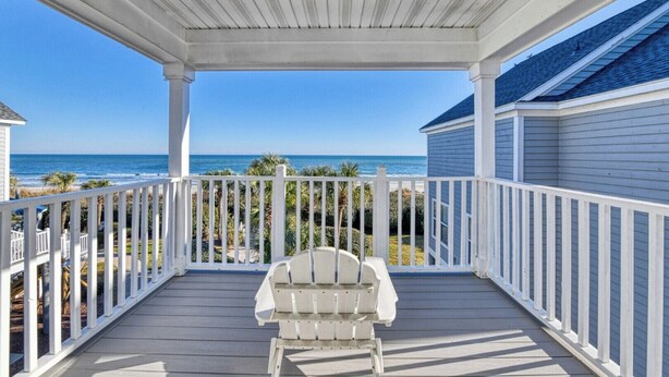 A covered porch with a white railing, a single white chair, and a view of the ocean. - Oceanfront 4 Bedroom, 3 Bath with Community Pool (Garden City Beach)