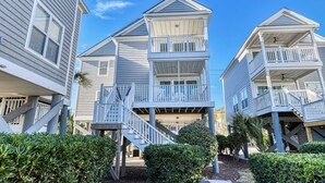 A beachfront property with multiple-story buildings featuring balconies and staircases leading to the ground level. - Oceanfront 4 Bedroom, 3 Bath with Community Pool (Garden City Beach)