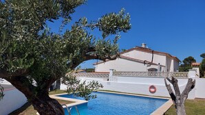En swimmingpool med et hvidt hus i baggrunden.
