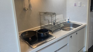 A kitchen with a stove, two pots, a sink, and a metal rack. - B&B Yuigahama (Kamakura)