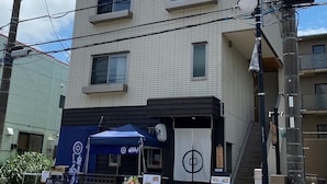 A two-story building with a blue awning and a signboard. - B&B Yuigahama (Kamakura)