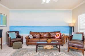 Enjoy the serene ocean view from the comfort of this stylish living room, featuring a sofa, armchairs, and a coffee table.