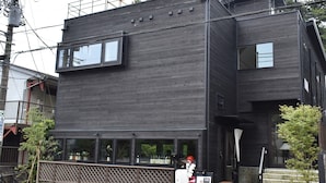 A modern two-story building with a dark exterior, large windows, and a small outdoor seating area with a bench and a table. - B&B Kamakura (Kamakura)