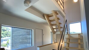 A modern interior with a wooden staircase, large windows, and a door. - B&B Kamakura (Kamakura)