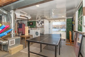 A room with a ping pong table, a washing machine, and a grill. - Lake Hopatcong Lake House - Private Dock, Game Room, kayaks, canoe and Grill (Lake Hopatcong)
