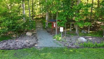 A forested area with a small red structure, possibly a shelter or information point, near a dirt path.