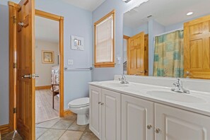 A bathroom with a white sink, wooden cabinets, a toilet, and a shower curtain.