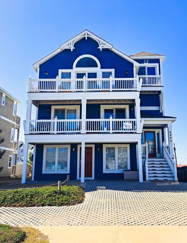 A two-story residential building with a balcony on the upper floor, a front entrance with a door, and a staircase leading to the entrance.