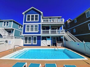 A two-story building with a swimming pool, a balcony, and a staircase.