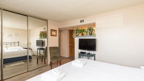 Een hotelkamer met een bed, een stoel, een televisie en een spiegel.