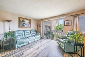 Un salón con un sofá de cuero verde, un sillón a juego, una mesa de centro de madera y una planta en maceta.
