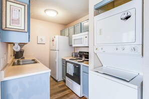 A compact kitchen with a sink, refrigerator, microwave, stove, and oven.