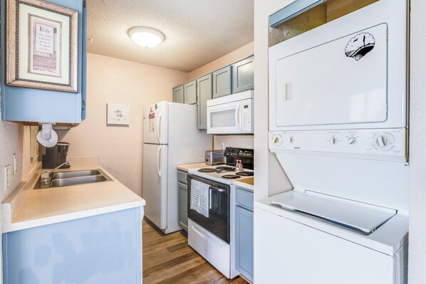 A compact kitchen with a sink, refrigerator, microwave, stove, and oven. - First-Floor Waterfront Escape | Pool & Fishing Dock Access (CORPUS CHRISTI)