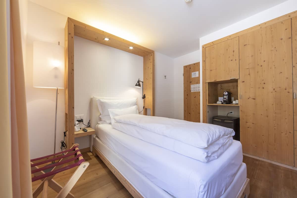 A bedroom with a wooden bed, a desk with a lamp, and wooden wardrobes.