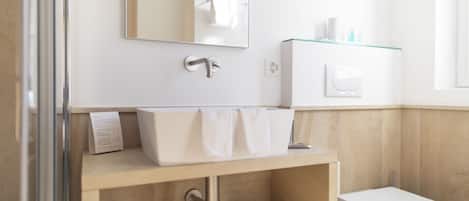 Un baño moderno con un lavabo blanco, un espejo y un inodoro.