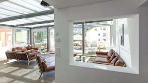 A modern living room with a large window, leather sofas, and a glass coffee table. - Hotel Müller Mountain Lodge (Pontresina)