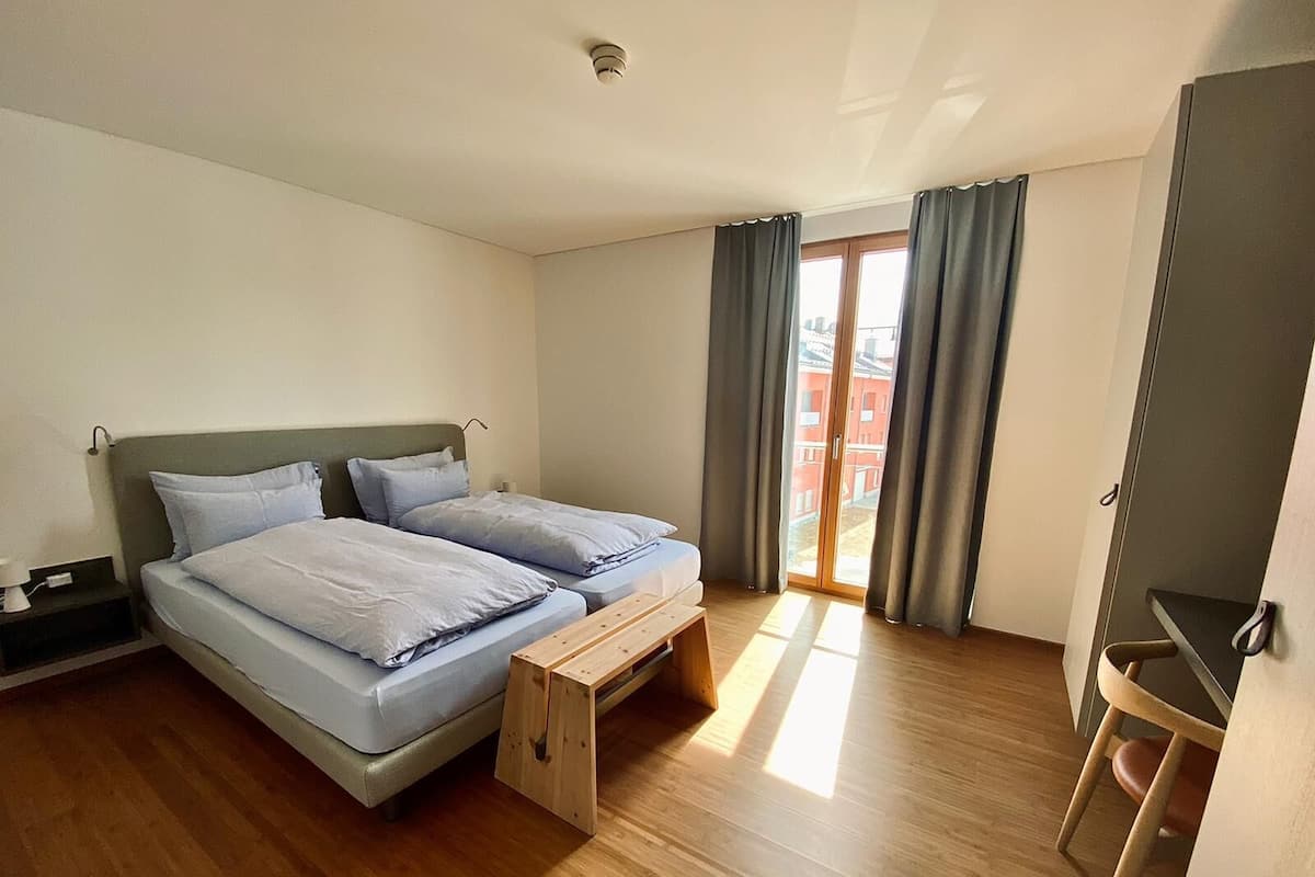 A bedroom with a bed, a desk, and a sliding glass door to an outdoor balcony.