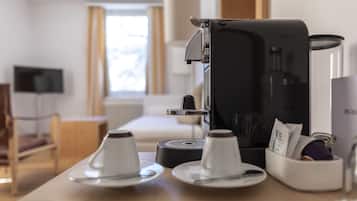 Una cafetera sobre una mesa con dos tazas y un recipiente pequeño.