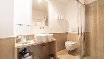 A modern bathroom with a glass shower enclosure, a vanity with a mirror, and a toilet.