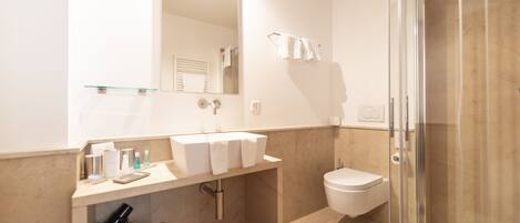 A modern bathroom with a glass shower enclosure, a vanity with a mirror, and a toilet.