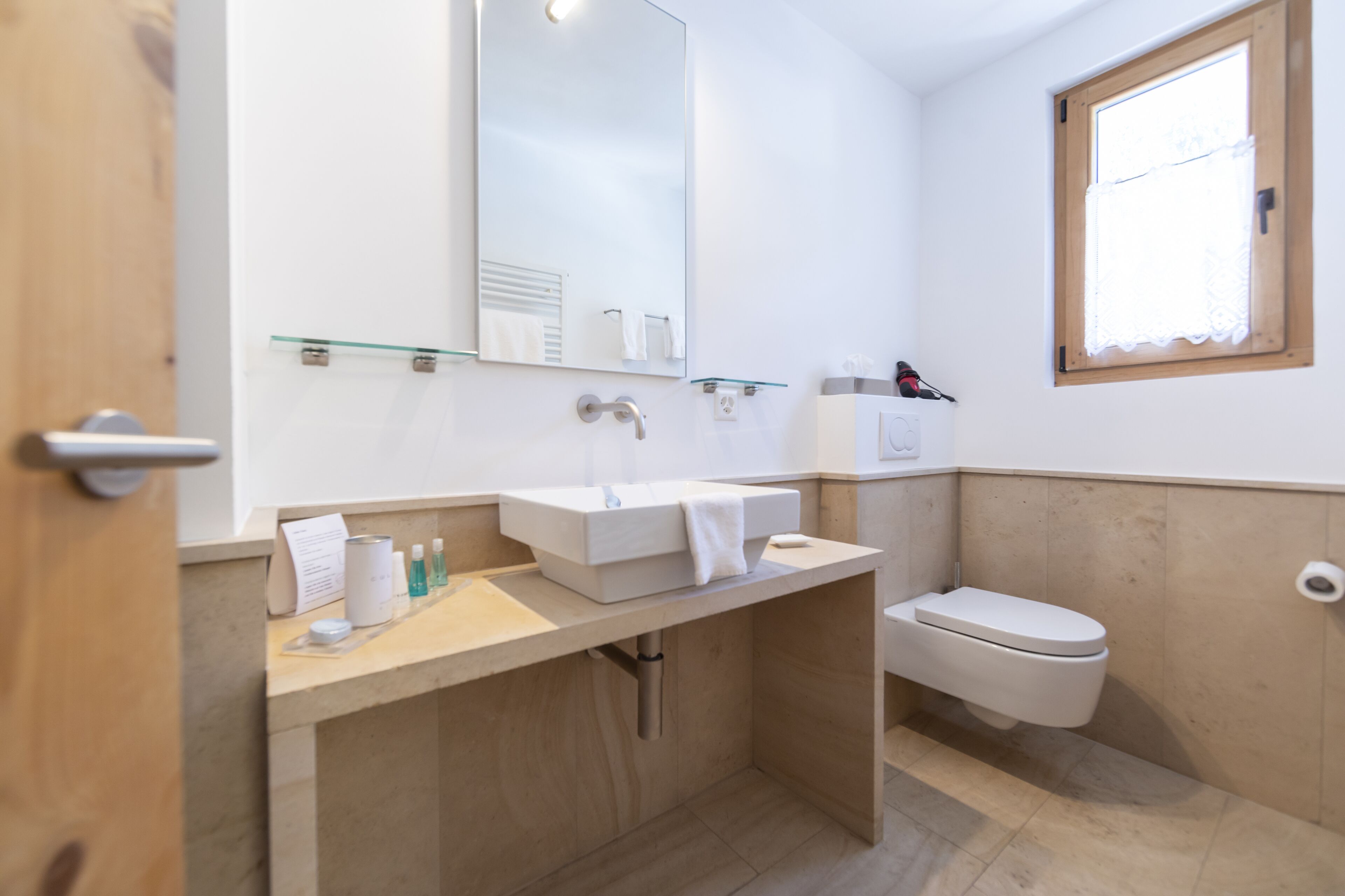 A modern bathroom with a white sink, mirror, and toilet.