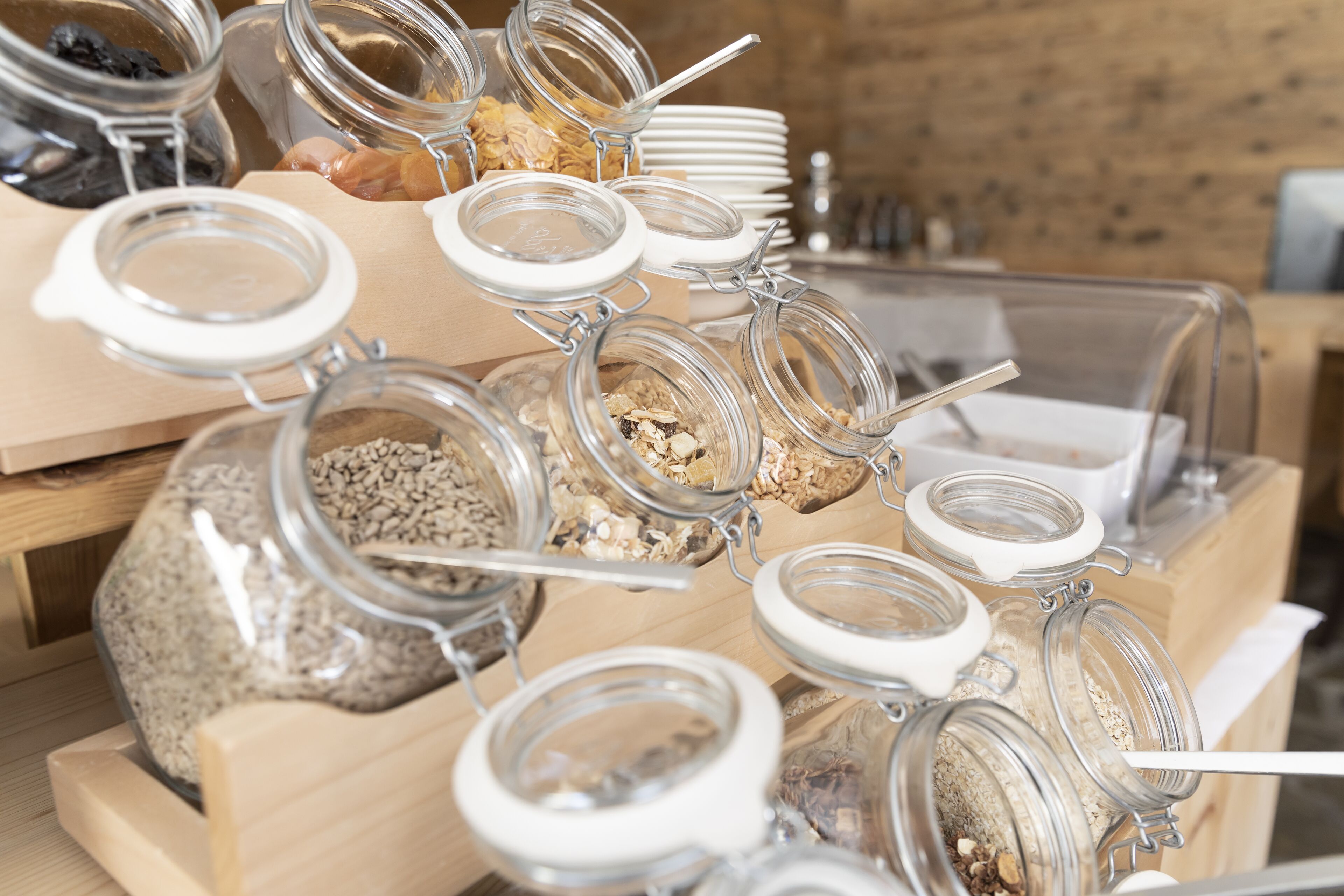 Un buffet composé de différents plats présentés dans des bocaux et des bols en verre, disposés sur des présentoirs en bois.