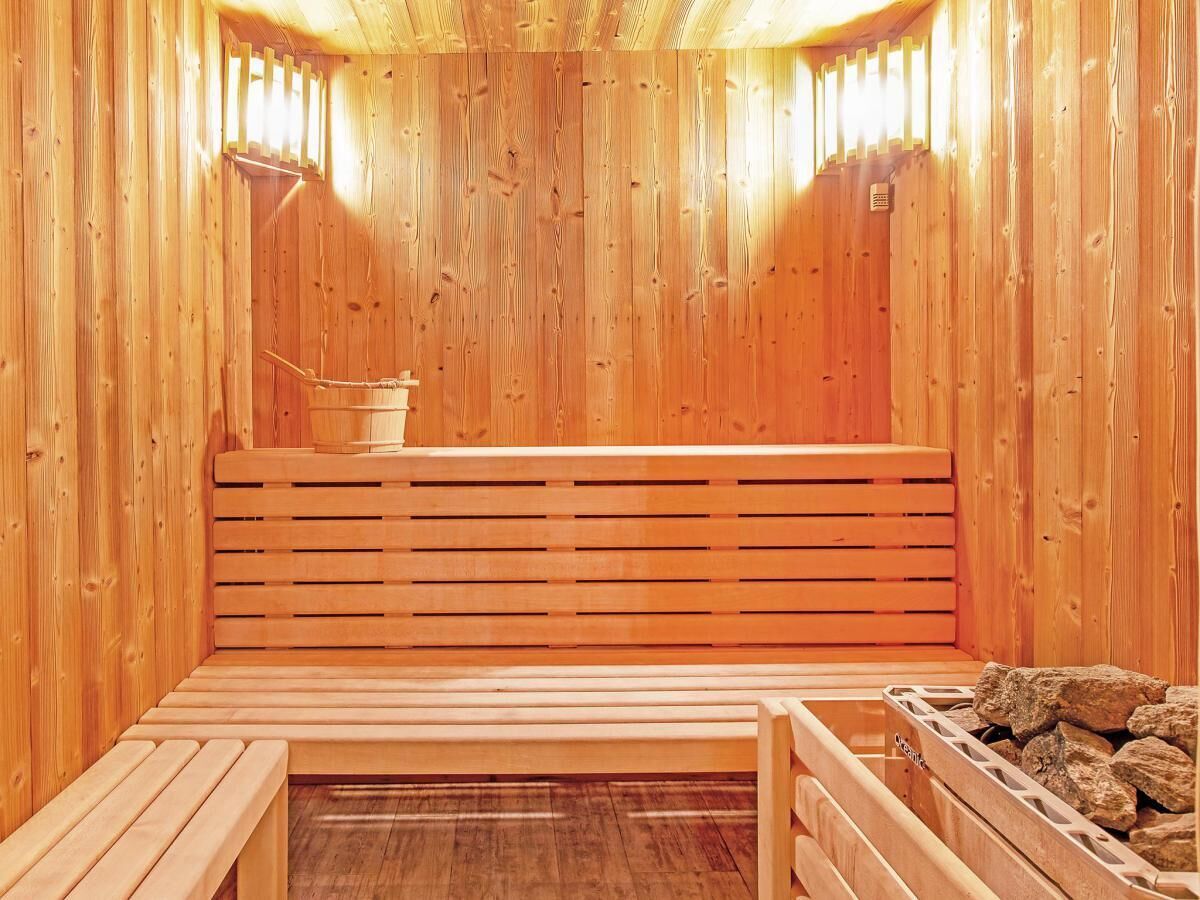 A wooden sauna with benches and a bucket.