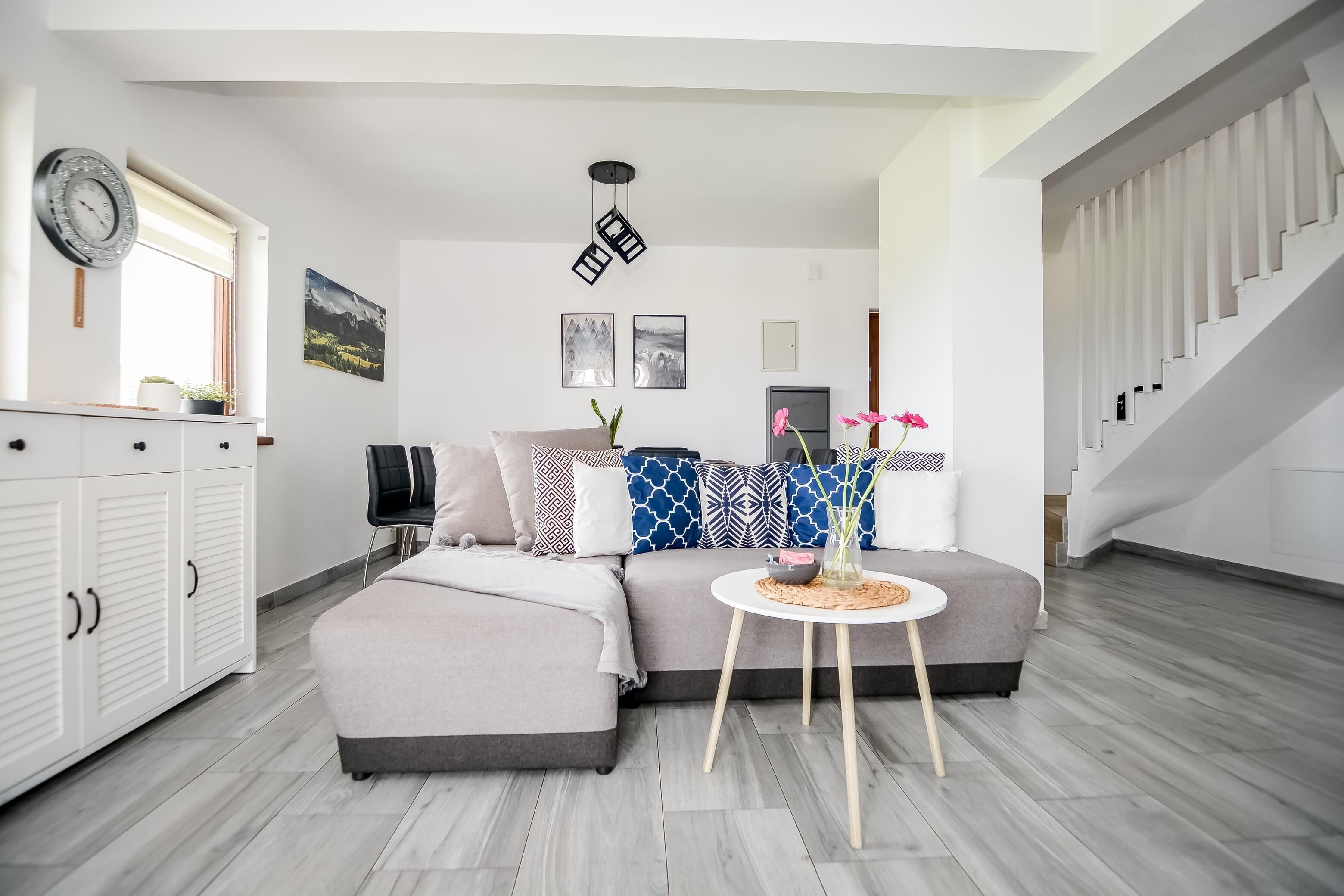 A modern living room with a grey sofa, a round coffee table, and a staircase.