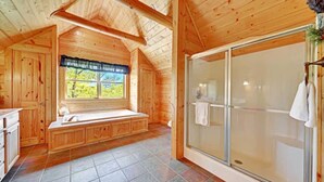 Ein Holzblockhaus-Interieur mit einer großen Schiebeglastür, einer Duschkabine, einer eingebauten Sitzbank mit Blick auf Grünflächen und einem gefliesten Boden.