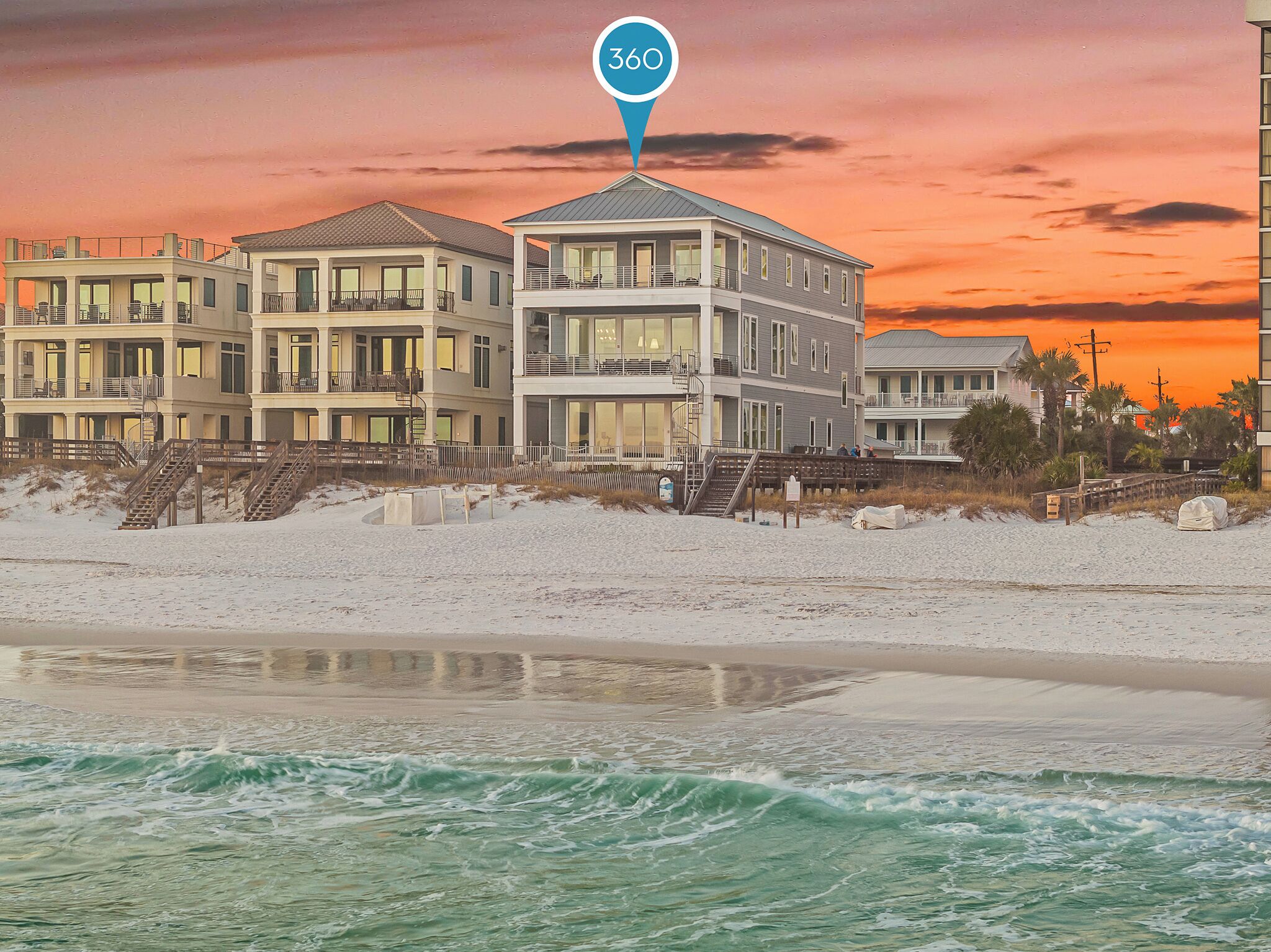 A beachfront hotel with multiple balconies, a beach view, and a sunset in the background.