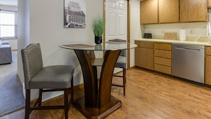 Une cuisine moderne avec des meubles en bois, une table à manger avec un plateau en verre et deux chaises rembourrées.