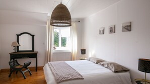 Un dormitorio con una cama, un escritorio, una silla, una lámpara y una ventana con cortinas.