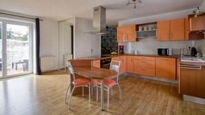 Una cocina moderna con armarios de madera, una isla central con asientos y vista a un patio exterior.