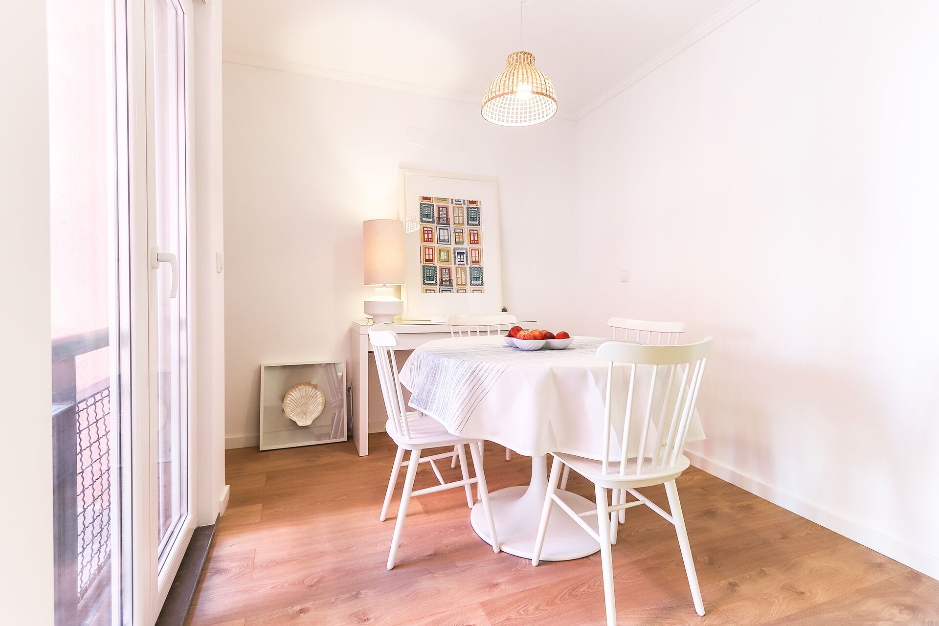 A dining area with a white table and chairs, a chandelier, and a wall with framed pictures.