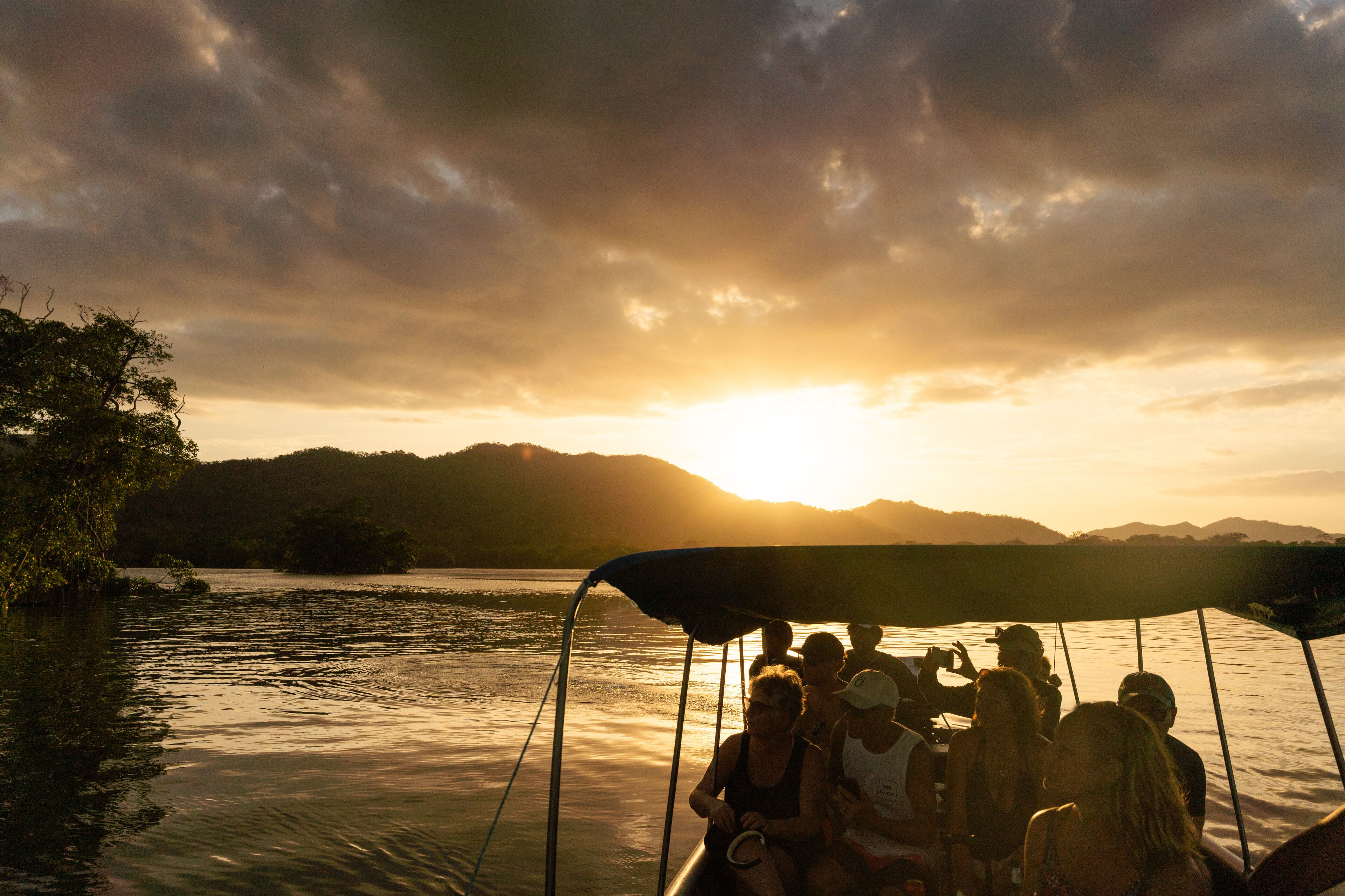 Un grupo de personas en un barco durante la puesta de sol.