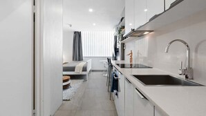 A modern kitchen with white cabinetry, a stainless steel sink, and a built-in oven.