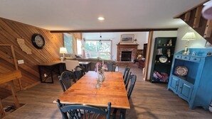 A dining area with a wooden table and chairs, a fireplace, and a blue cabinet with decorative items. - Snowcreek Resort Vacation Rental 217 (Mammoth Lakes)