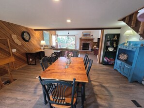 A dining area with a wooden table and chairs, a fireplace, and a blue cabinet with decorative items.
