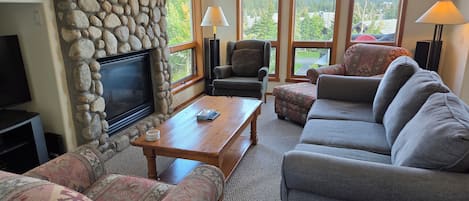 A living room with a stone fireplace, a television, and a sofa.