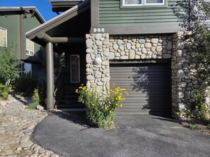 Een huis met een stenen gevel, een garagepoort en een kleine tuin met gele bloemen.