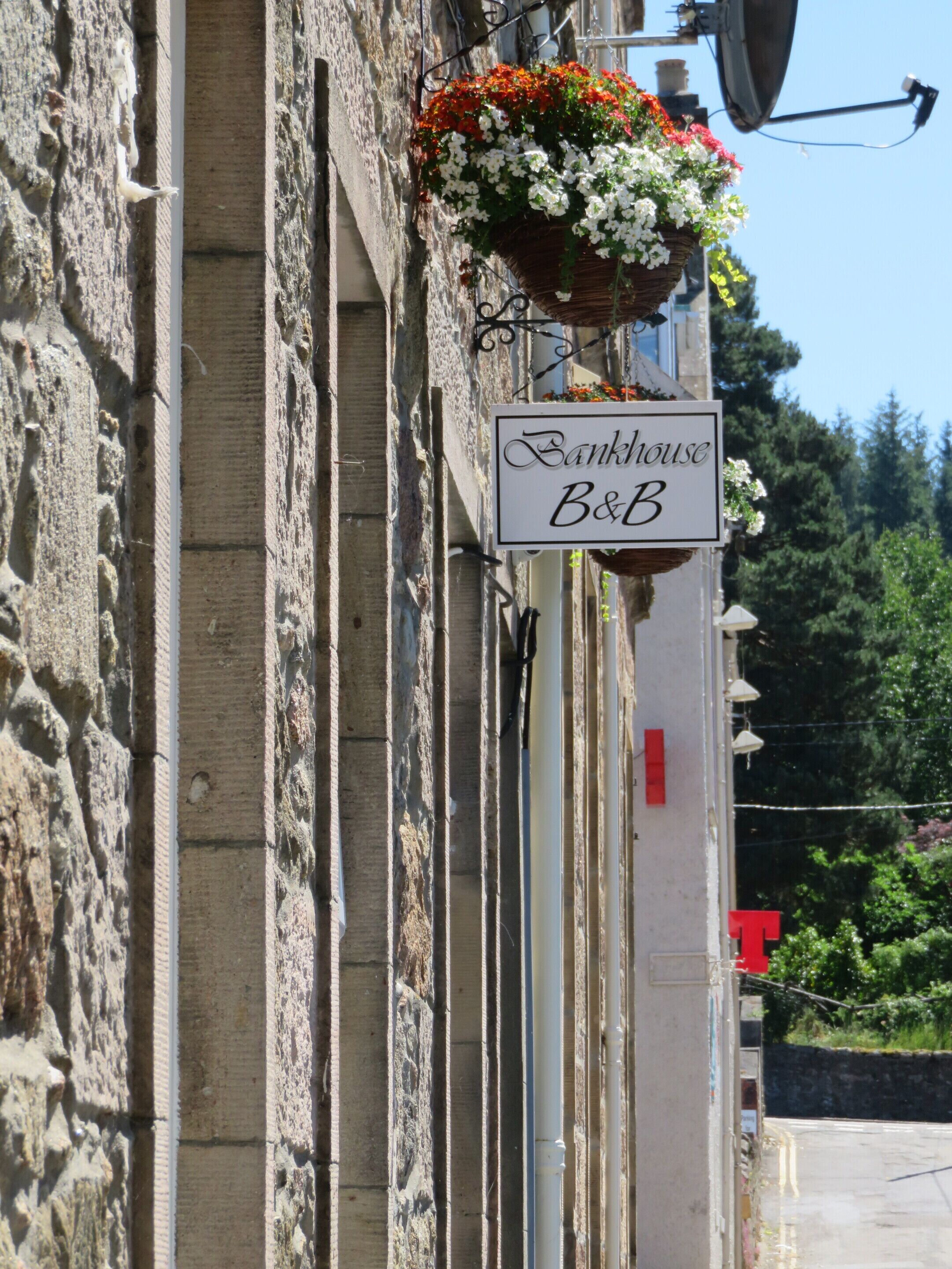 A building with a sign reading "Bankhouse B&B" and a hanging flower basket.