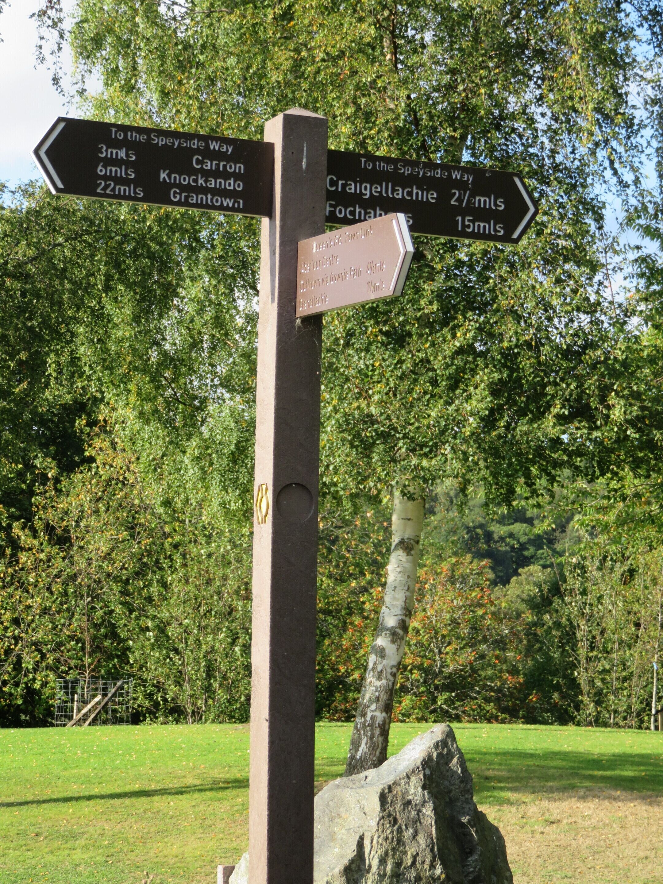 A directional signpost with multiple arrows pointing towards various destinations and distances.
