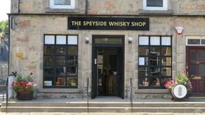 A stone building with a sign reading "The Speyside Whisky Shop". - Bankhouse B&B (Aberlour)