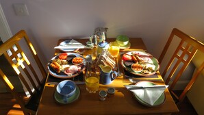 A breakfast table with plates of food, glasses of orange juice, and a pitcher of juice. - Bankhouse B&B (Aberlour)