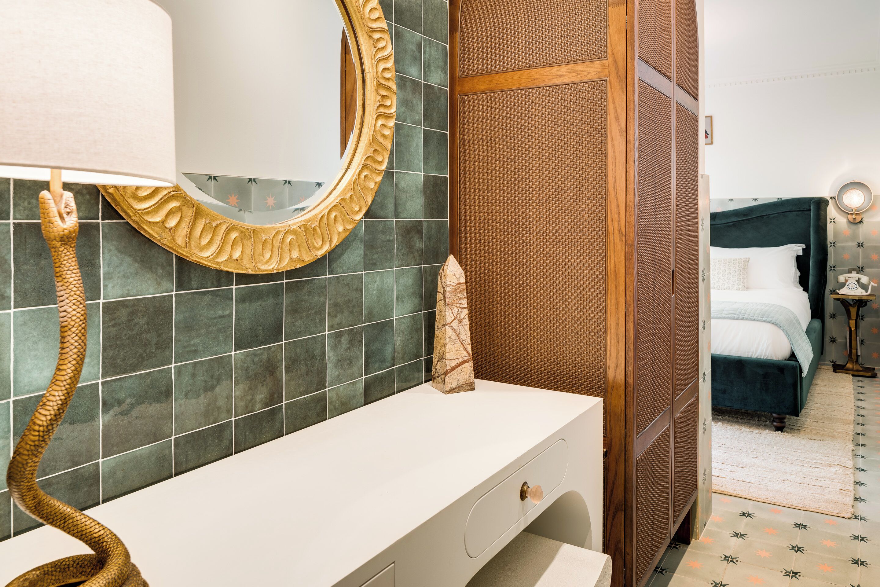 Un baño con un toallero con forma de serpiente, un espejo con un marco ornamentado y un tocador blanco.