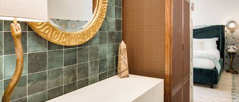 Un baño con un toallero con forma de serpiente, un espejo con un marco ornamentado y un tocador blanco.